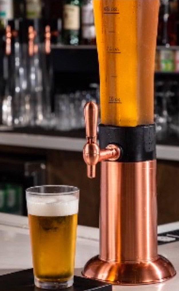 A copper beer tower filled with lager beside a poured pint glass on the KPOT Middletown bar